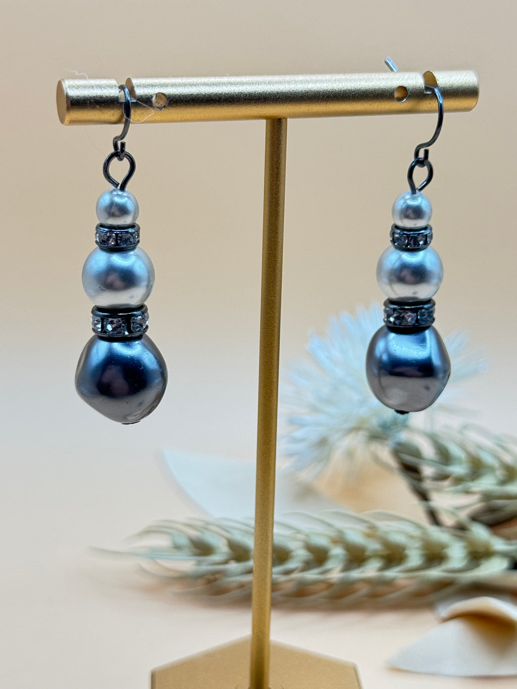 Elegant pierced earrings featuring round faux pearl studs with elongated faux pearl teardrop dangles. Gold tone accents add a classic, polished finish.